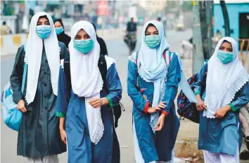  ?? AFP ?? Students walk through a street to their school in Karachi on Wednesday after the educationa­l institutes were reopened after nearly six months.