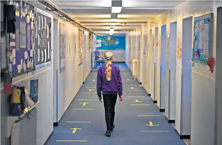  ??  ?? A pupil walks to her class at Outwood Primary Academy Park Hill in Wakefield, West Yorks shortly before the half-term break. The Government has said children should not use playground­s if they have access to a garden