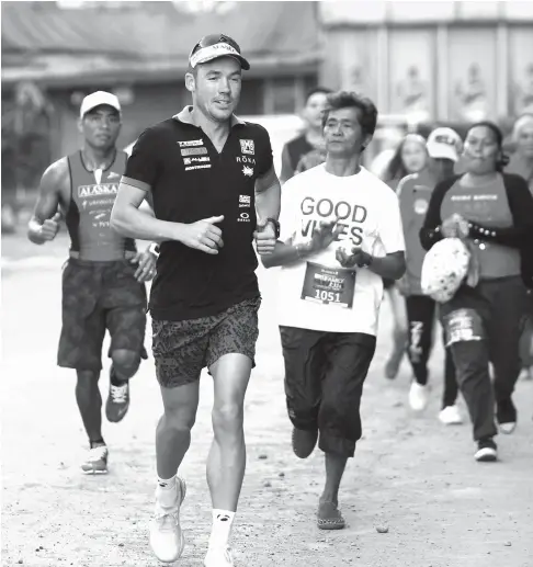 ?? CONTRIBUTE­D PHOTO BY GARY SATO ?? FAMILY RUN. Alveo Ironman 70.3 Davao contender Tim Reed and Filipino elite triathlete August Benedicto join the Alaska Family Run at People’s Park yesterday, one of the side events for tomorrow’s main event.