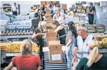  ?? ?? Die Packstraße in der Messehalle 8b: 40 Helfer füllen in der ersten Schicht unter anderem Nudeln, Fertigsupp­en, Ananas und H-Milch in die Kartons. Zu ihnen gehört auch Hans-Gerhard Kall (vorne rechts mit weißer Weste).