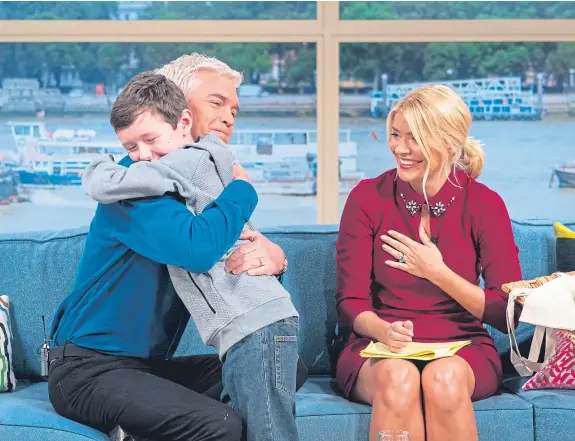  ?? Picture: Shuttersho­ck. ?? Phillip Schofield and Holly Willoughby giving wannabe presenter Michael Glaister a hug on This Morning.