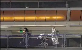  ?? Brian van der Brug Los Angeles Times ?? A PASSENGER pushes a stroller on New Year’s Eve at LAX. An advisory urges California­ns to stay home or in their region and avoid nonessenti­al travel.