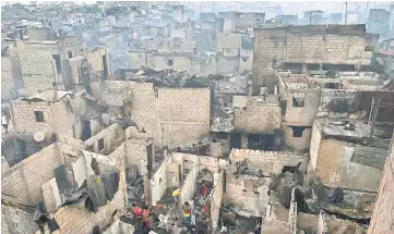  ??  ?? Smoke billows from houses gutted by a fire overnight in an informal settlers area, near the south harbour port, in Manila. — AFP photo