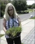  ?? AP PHOTO/JULIO CORTEZ ?? In this July 5 photo, Judy Rutan holds a section of grass that she said was dug up by surveyors on her front yard, at her home in Eatontown, N.J.