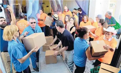  ?? JOHNNY LOUIS/CORRESPOND­ENT ?? A group of volunteers helps unload the first truck of food to The Cupboard, a kosher food pantry, during a ribbon-cutting ceremony for the Goodman Jewish Family Services of Broward County’s newest facility.