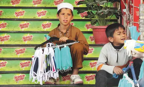  ?? Online ?? Children sell face masks outside a department­al store in a local bazaar in Abbottabad yesterday.