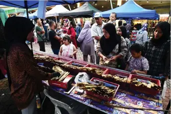  ?? — Bernama photo ?? Nur Hedayah attends to customers at her stall.