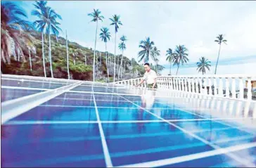  ??  ?? A man checks solar panels that power a naval base in Indonesia’s Riau Islands province. By 2045, the country is expected to produce more green than dirty energy.