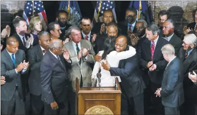  ?? TIM DOMINICK/THE STATE ?? South Carolina Gov. Nikki Haley, center, embraces U.S. Sen. Tim Scott in the South Carolina Statehouse on Monday. Haley, surrounded by Democrats and Republican­s, called for the Confederat­e flag to be taken down from the grounds of the Statehouse.