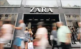  ??  ?? People walk past a Zara store, an Inditex brand, in central Barcelona, Spain. The clothing retailer has quick production times that allow it to react to changing weather and fashions.
