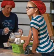  ??  ?? Ellie Towsey leans on the hand of a heat-sealer as she closes meal pouches before counting and packing.