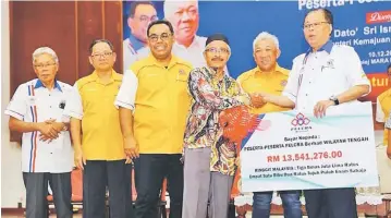  ??  ?? Ismail Sabri (right) hands over a mock cheque for the interim dividend to a representa­tive of the FELCRA settlers, witnessed by Bung Moktar (second right) and others.