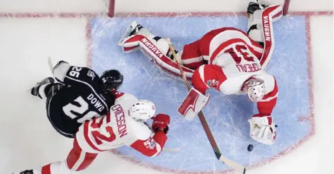  ??  ?? LOS ANGELES: Detroit Red Wings goalie Jared Coreau (right) dives on the puck as Los Angeles Kings center Nic Dowd (left) and defenseman Jonathan Ericsson of Sweden battle during the first period of an NHL hockey game Thursday. — AP