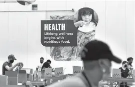  ?? JACQUELYN MARTIN/AP ?? Volunteers pack boxes of food for distributi­on last week at The Capital Area Food Bank in Washington.