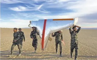  ?? Iranian Army ?? As U.S. sanctions resumed, Iranian state television broadcast military maneuvers, which included missiles downing a drone. An Iranian Army photo shows soldiers carrying wreckage.