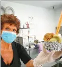  ??  ?? A woman wearing a surgical mask prepares a cup of ice cream.