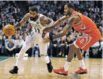  ?? MICHAEL DWYER/THE ASSOCIATED PRESS ?? The Celtics’ Kyrie Irving, left, drives past the Rockets’ Trevor Ariza during Thursday’s game. The Celtics rallied from a 26-point deficit to beat Houston 99-98.