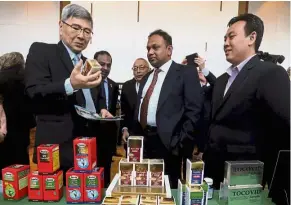  ??  ?? Good potential: Mah reading the benefit of a palm-based health product displayed on the packaging box at the Palm Internatio­nal NutraCosme­ceutical conference in Putrajaya.