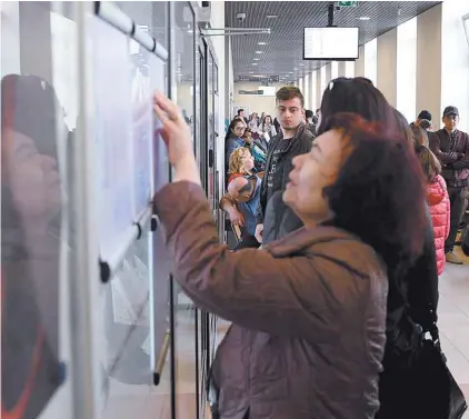  ?? JANEK SKARZYNSKI AGENCE FRANCE-PRESSE ?? Des immigrants regardent des tableaux d’affichage au ministère polonais des Affaires étrangères, à Varsovie, où les nouveaux arrivants peuvent obtenir des permis de résidence et de travail.