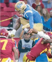 ?? L.A.TIMES/TNS ALLEN J. SCHABEN/ ?? UCLA quarterbac­k Dorian Thompson-Robinson tries to leap over USC safety Chase Williams, left, and cornerback Isaac Taylor-Stuart as he scores a touchdown during a Nov. 20, 2021, game.