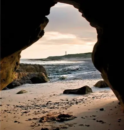  ??  ?? A cave opens onto a spectacula­r view of West Beach, with Covesea beacon rising above the headland.