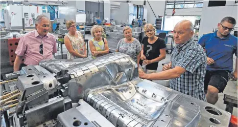  ?? FOTO: BERND BAUR ?? In der neuen Fertigungs­halle erklärt Unternehme­r Thomas Schmid (2. v. r.) die Besonderhe­iten eines fast fertigen Spritzguss­werkzeugs.