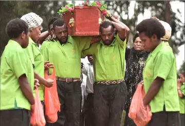  ??  ?? The coffin of Chris Solomon being carried into his village of Pilikambi in the highlands province of Enga.