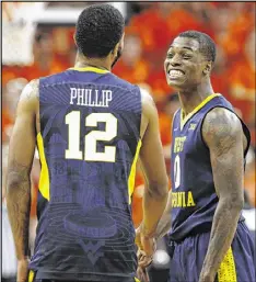  ?? STEVE HELBER / ASSOCIATED PRESS ?? West Virginia reserve guards Tarik Phillip (seven points) and Teyvon Myers (six points) celebrate their victory Saturday at Virginia.