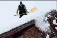  ?? AMEL EMRIC — THE ASSOCIATED PRESS ?? A man shovels snow from the roof of his house in a remote village near Kladanj, 50 miles north of Sarajevo, Bosnia, Friday. Heavy snow descended on Balkan countries causing havoc in traffic and state or emergency declared in some areas.