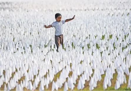  ?? JACK GRUBER/ USA TODAY ?? Walter Larkin walks amid an artist’s installati­on in Washington, D. C., in October honoring the nearly 240,000 people who have died from COVID- 19. Like in the spring, a winter surge could overwhelm many U. S. hospitals.