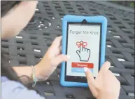  ??  ?? Marissa Manzo holds a phone with Forget Me Knot, an app that lets students access their scheduled homework.