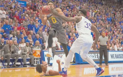  ?? | GETTY IMAGES ?? Arizona State’s Tra Holder splits Kansas defenders Devonte’ Graham ( lying on court) and Udoka Azubuike on Sunday in Lawrence, Kan.