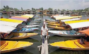  ?? — Reuters ?? A boatman walks past the parked ‘Shikaras’ or boats for tourists on the banks of Dal Lake in Srinagar, India, on Sunday.