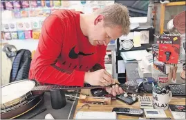  ??  ?? Banjo player and music-store owner Stevie Barr prepares his instrument for the night’s performanc­e in Galax, Va.