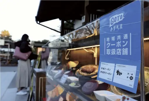  ?? The Yomiuri Shimbun ?? A Go To Travel poster is displayed at a restaurant and souvenir shop near Nagoya Castle on Monday.