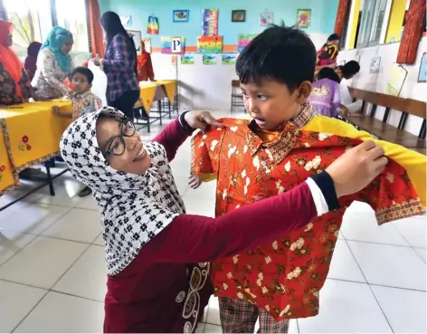  ?? AHMAD KHUSAINI/JAWA POS ?? SEKOLAH BARU: Kasiatun mengukur seragam batik untuk putranya, Devan Dwi Prasetyawa­n, saat melakukan daftar ulang di SDN Tanah Kali Kedinding 1, Kenjeran, kemarin (25/5).