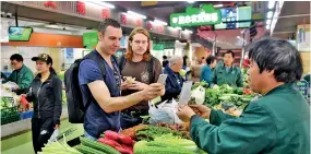  ??  ?? Tim Clancy (L Front), an Australian who has lived in Hangzhou for six years with his Chinese wife, took his American friend to buy vegetables through mobile payment at a market in Hangzhou, capital of east China’s Zhejiang Province, on April 14, 2017....