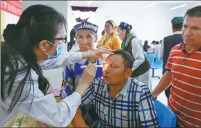  ?? XU ZHUZHU / FOR CHINA DAILY ?? Liu Weihua, an eye doctor from Beijing Tongren Hospital, checks a resident of Hotan, in the Xinjiang Uygur autonomous region, earlier this month.