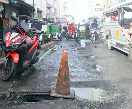  ?? PHOTOGRAPH BY AL PADILLA FOR THE DAILY TRIBUNE @tribunephl_al ?? RUTS and potholes dominate this road with an open manhole as incessant rains continue to drop in the metropolis making them impossible to vehicles.