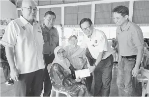  ??  ?? TERIMALAH: Lee menyerahka­n bantuan kepada warga emas, Jauyah Mat, 84, sambil disaksikan Adam (kiri) dan yang lain.