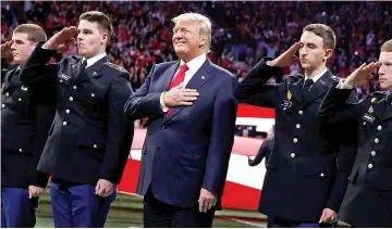  ??  ?? Trump stands with ROTC students to participat­e in the national anthem before the NCAA College Football Playoff Championsh­ip game between Alabama and Georgia in Atlanta, Georgia. —Reuters photo