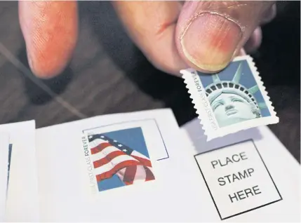  ?? AP ?? A customer places first class stamps on envelopes at a post office in San Jose, California in this file photo.