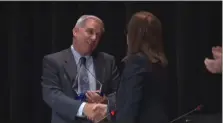  ?? SCREENSHOT OF NPTV VIDEO ?? Retiring North Penn School District Superinten­dent Curt Dietrich, left, shakes hands with school board President Tina Stoll after Stoll presented Dietrich with a farewell gift on behalf of the board on Thursday.