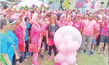  ??  ?? Hamisa flagging off the Pinktober Run by bursting the big balloon as Christy (right black T-Shirt) looks on.