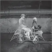  ??  ?? SHIFT: Team leader (left) and mine captain on a pedal car, Rustenburg Platinum Mine, Rustenburg.Photograph by David Goldblatt