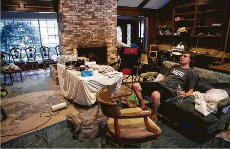  ?? Brett Coomer Photos / Houston Chronicle ?? James Slaughter rests in his living room as his flood-damaged home is renovated. Below, Amy Slaughter sits in a greenhouse converted into an air-conditione­d office. The family is in favor of a San Jacinto River dreding project to help alleviate flooding in Kingwood.