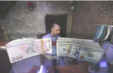  ??  ?? Banknotes of US dollars and Turkish lira are seen in a currency exchange shop in the city of Azaz, Syria. The downgrades prompted a new slide in the lira, which lost 2.2 per cent against the dollar to trade at 6.3. — Reuters photo