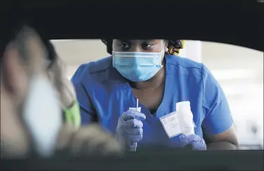  ?? WILFREDO LEE — ASSOCIATED PRESS ?? Healthcare worker Rahaana Smith instructs passengers how to use a nasal swab, at a drive-thru COVID-19 testing site at the Miami-Dade County Auditorium, in Miami in July.