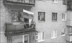  ?? ?? IN THIS HANDOUT
PHOTO TAKEN FROM VIDEO released by Russian Defense Ministry Press Service on Monday, a man sets a Russian national flag on a balcony of a residentia­l building in Lysychansk, which is now territory under the Government of the Luhansk People’s Republic control, eastern Ukraine.