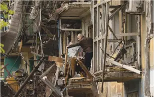  ?? (Jorge Silva/Reuters) ?? A MAN stands on the balcony of his apartment yesterday after a missile strike damaged the residentia­l building in Dobropilli­a, Donetsk.